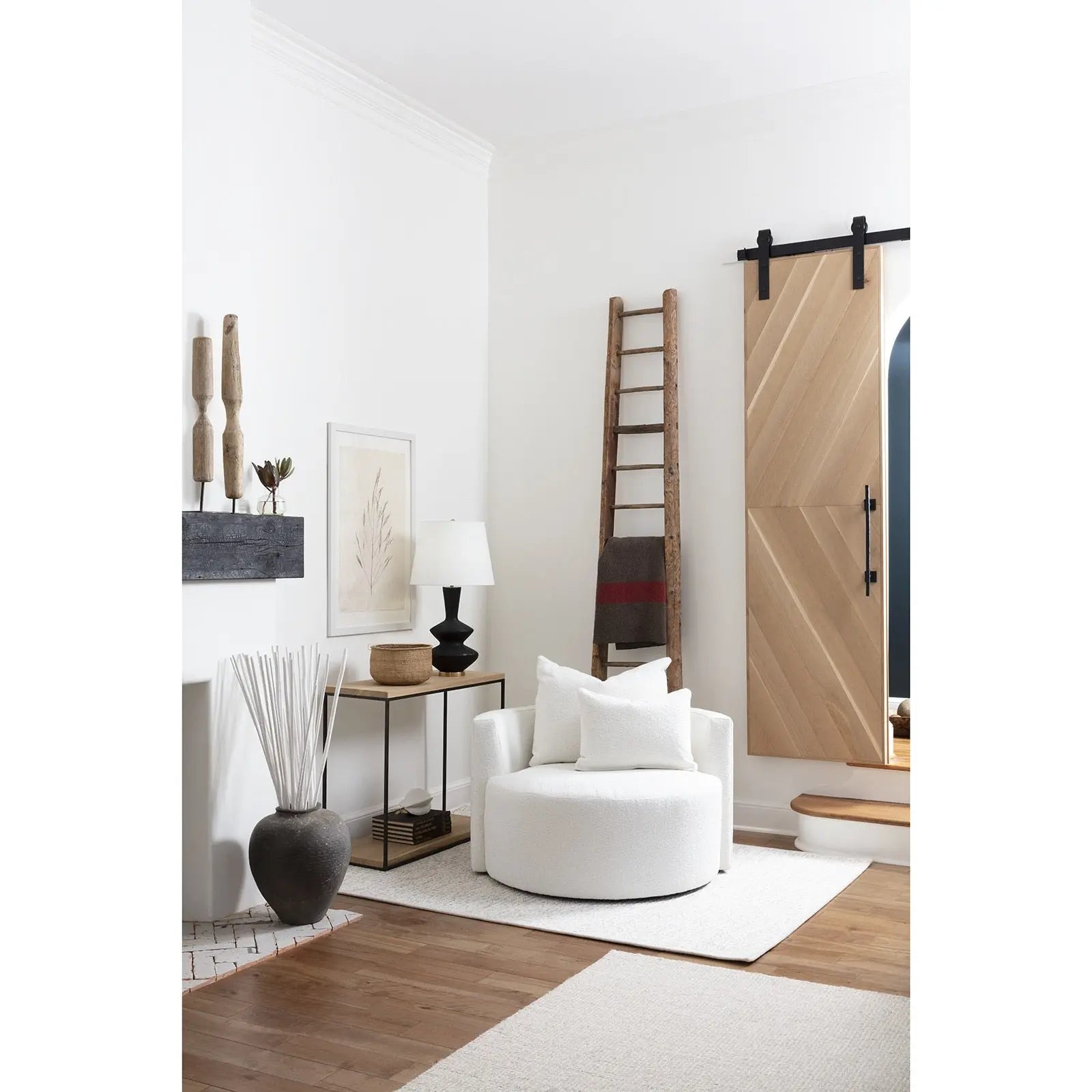 Modern living room with a white armchair, wooden ladder, and sliding barn door.
