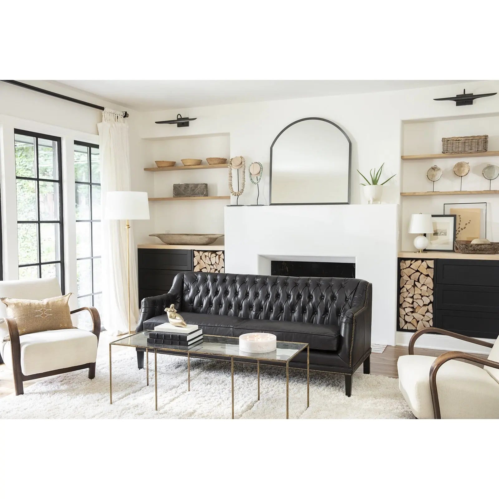 Modern living room with black leather sofa, white chairs, and decorative elements.