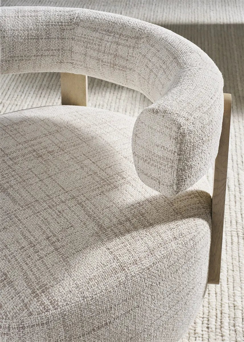 Daydream Swivel Chair, a modern, low-profile accent chair with a curved bolster back, upholstered in light Reynolds Linen fabric with exposed oak wood supports.