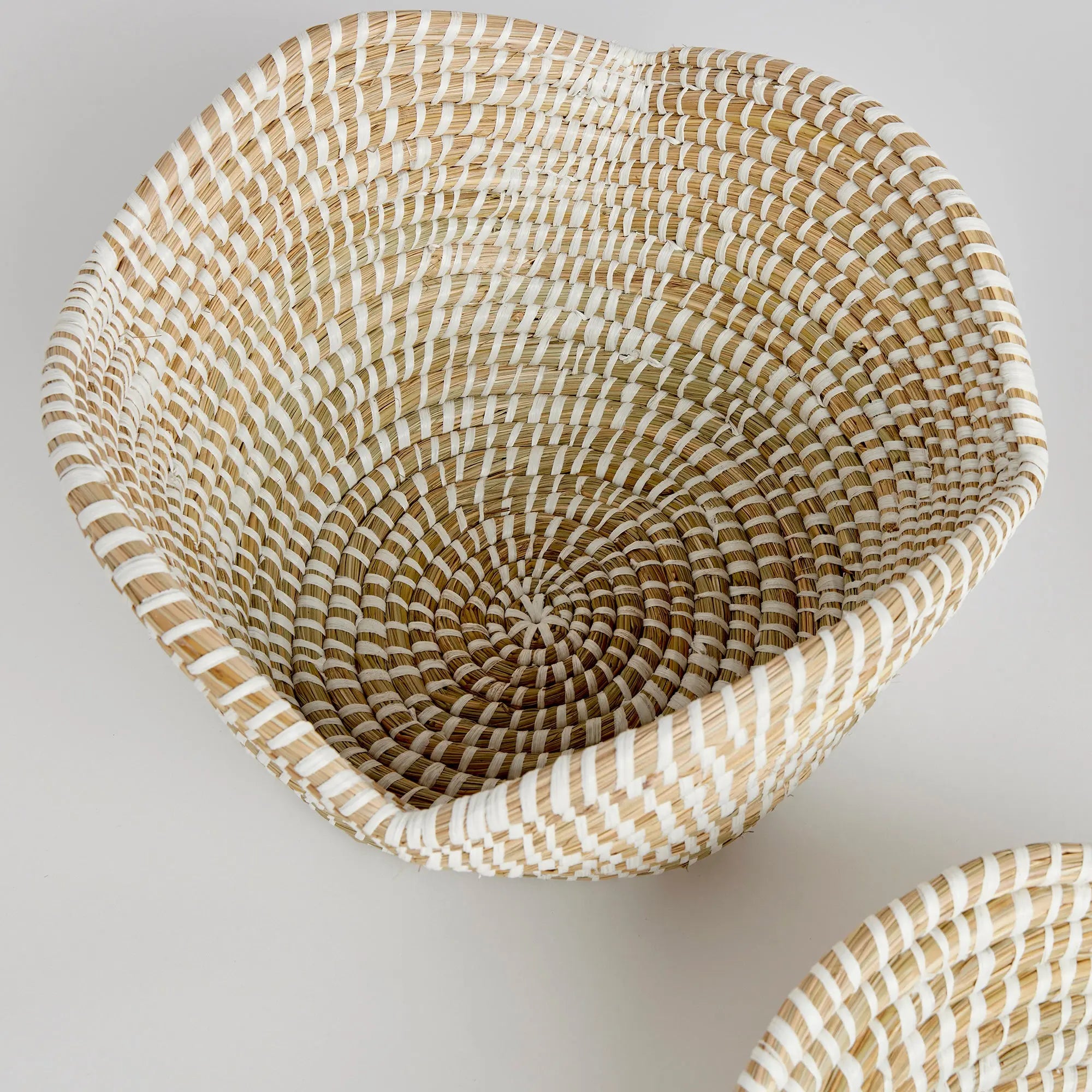 Woven basket with striped pattern on a light gray background