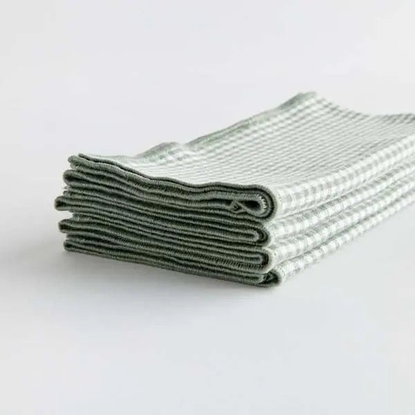 Set of four Viola Dinner Napkins made from soft, verdant green cotton, folded and tied with a grosgrain ribbon.
