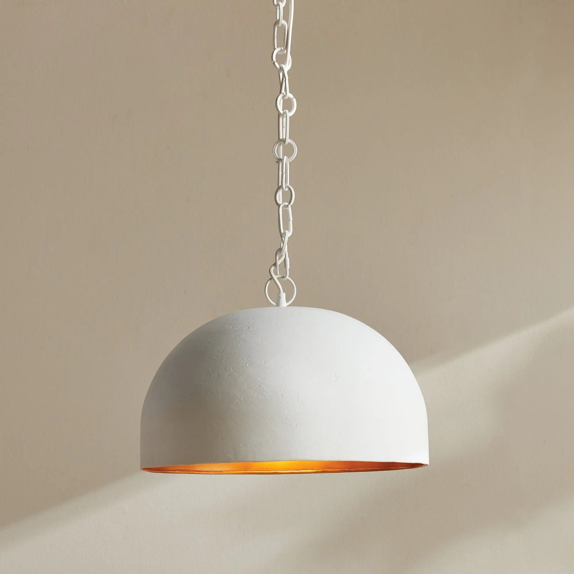 Concrete pendant light with a gold interior on a beige background