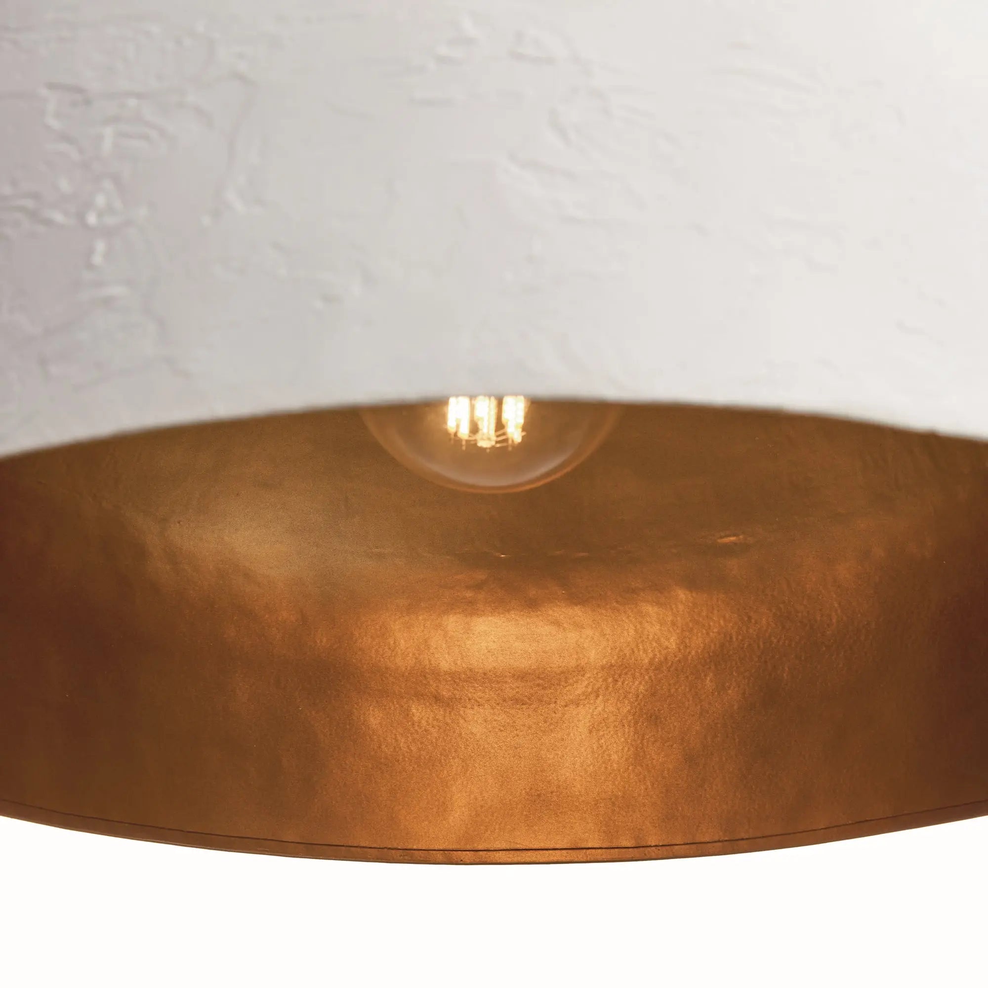 Close-up of a gold pendant light with a white wall background