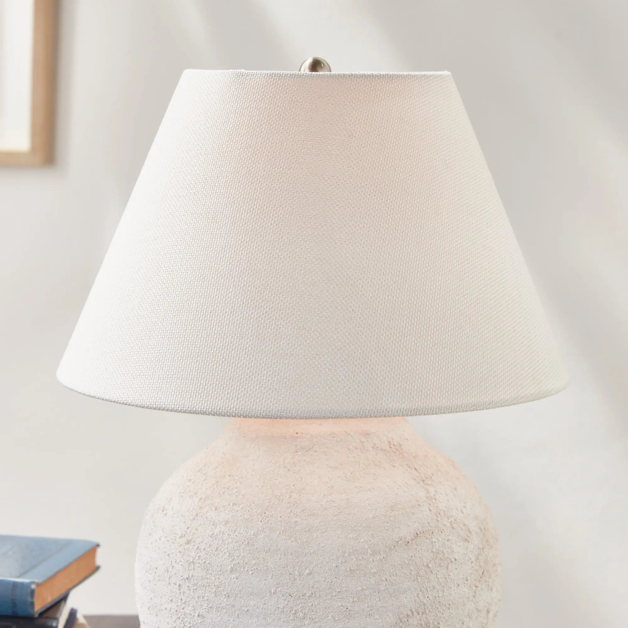 Theo Table lamp with a textured base and white shade on a neutral background
