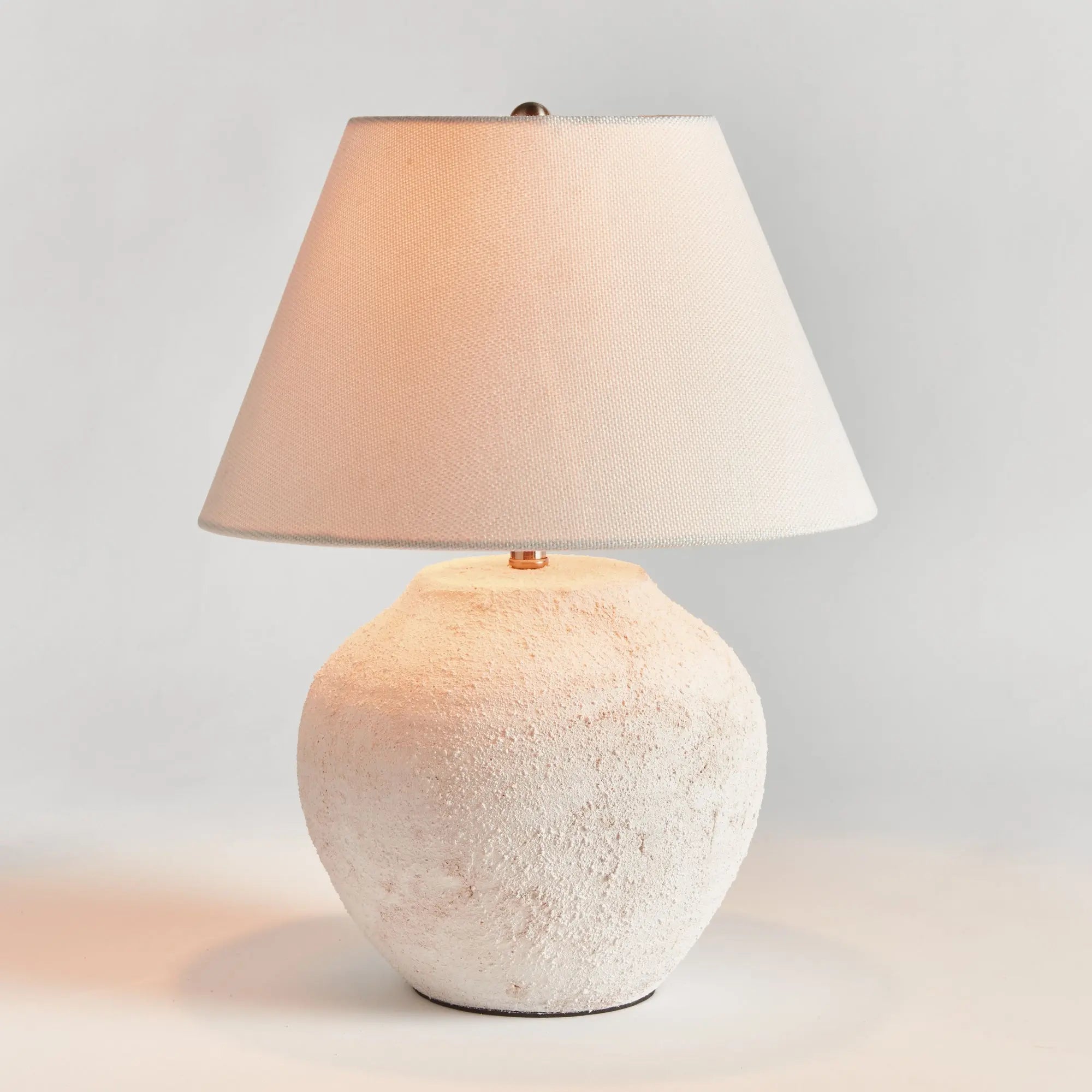 Theo Table lamp with textured white base and beige lampshade on a light gray background
