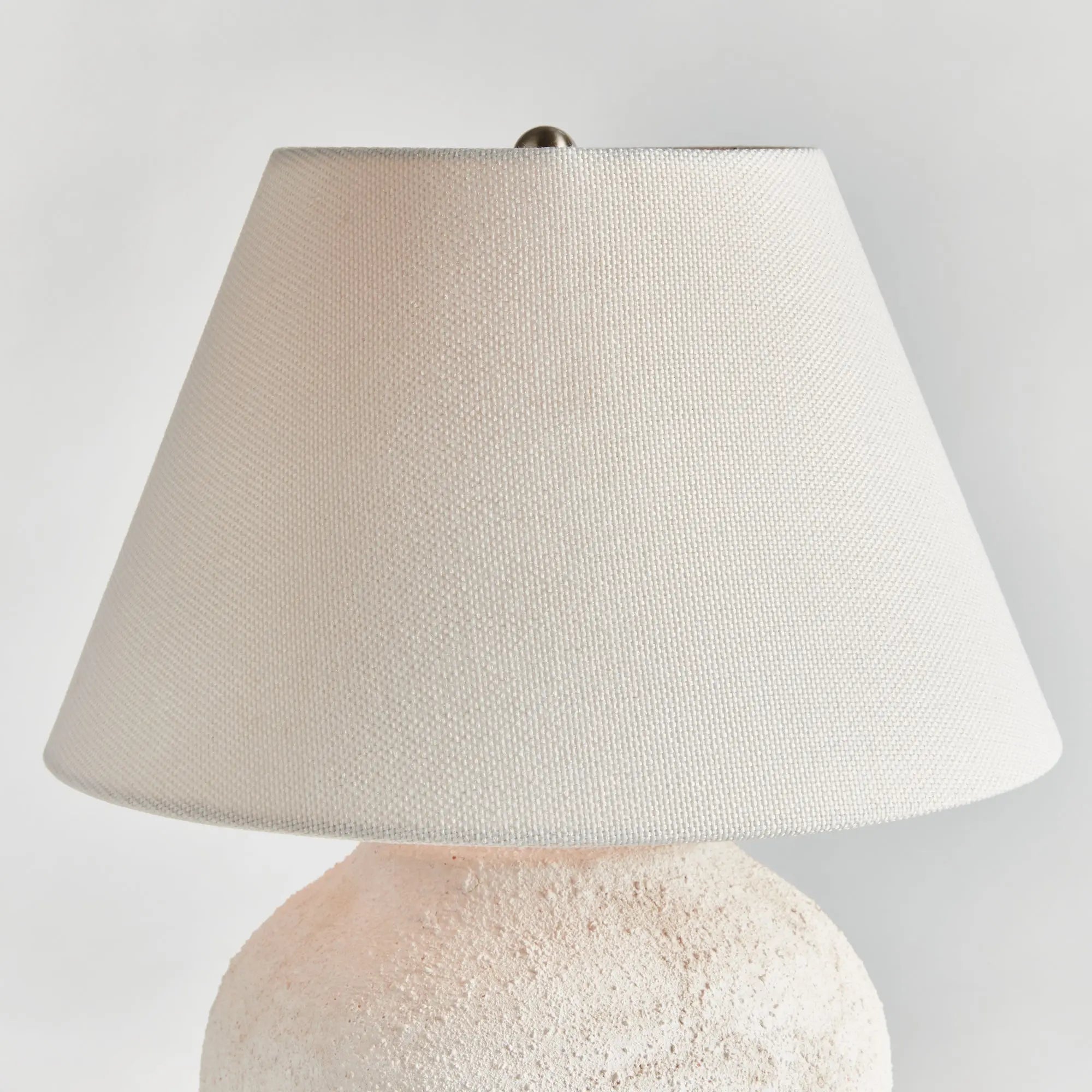 Theo Table lamp with textured beige shade and ceramic base on a light gray background