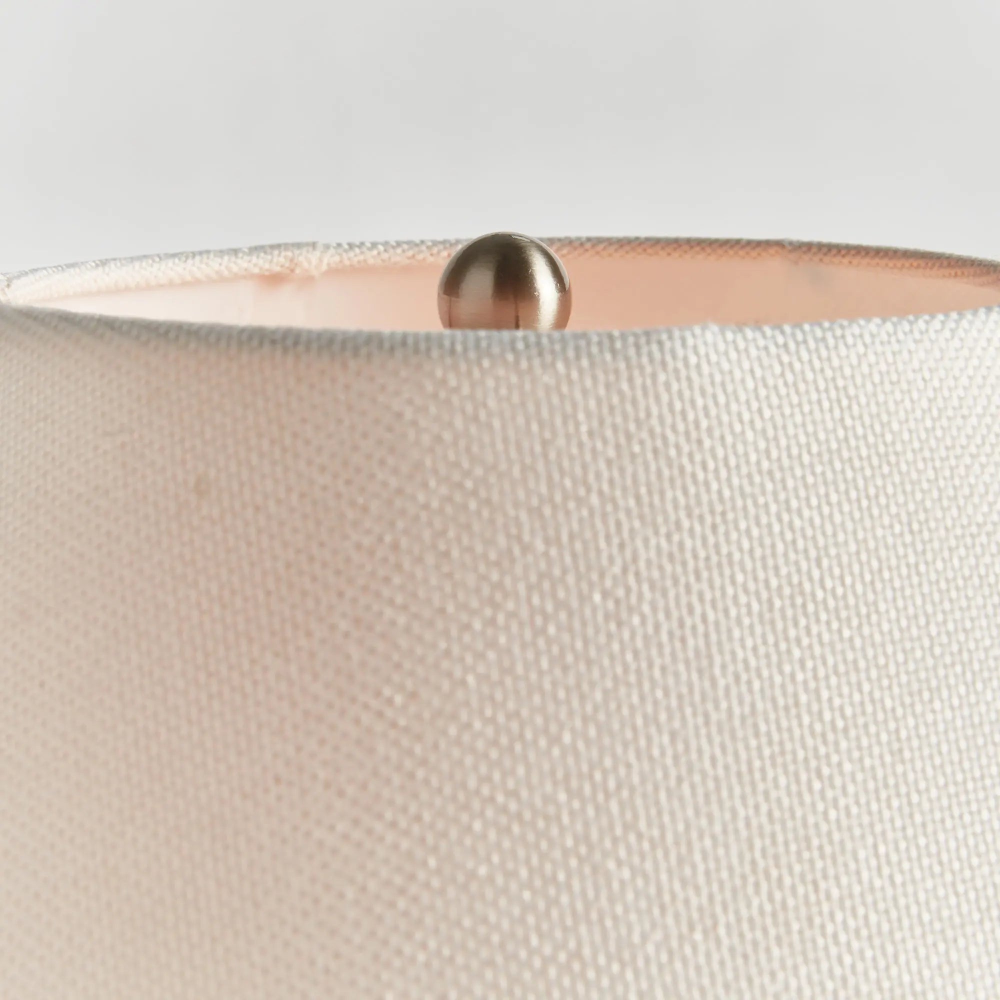Close-up of a beige fabric Theo lampshade with a rose gold base.