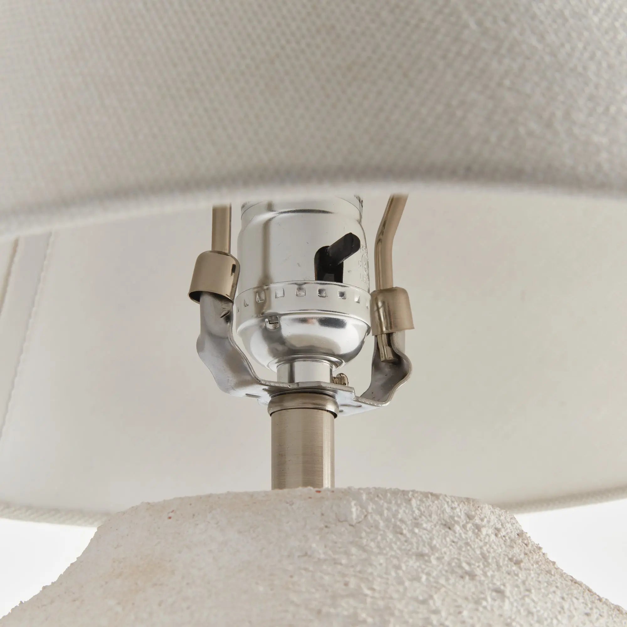 Theo Lamp Close-up of a lampshade with a metallic fitting and white fabric.