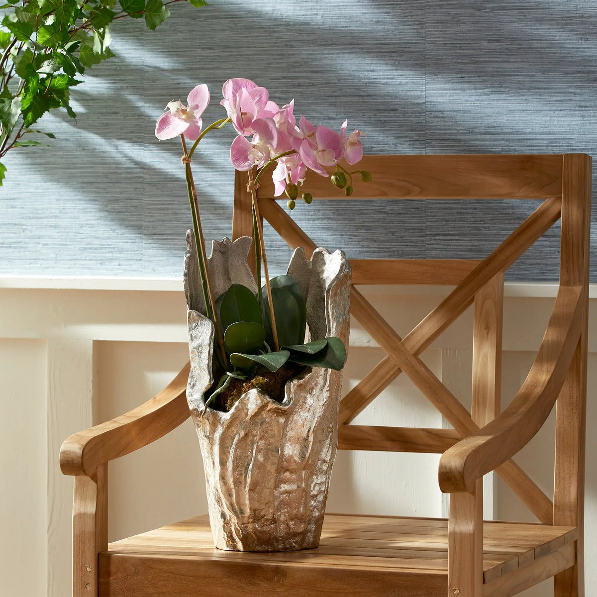 Arbre silver vase with a pink orchid near a window