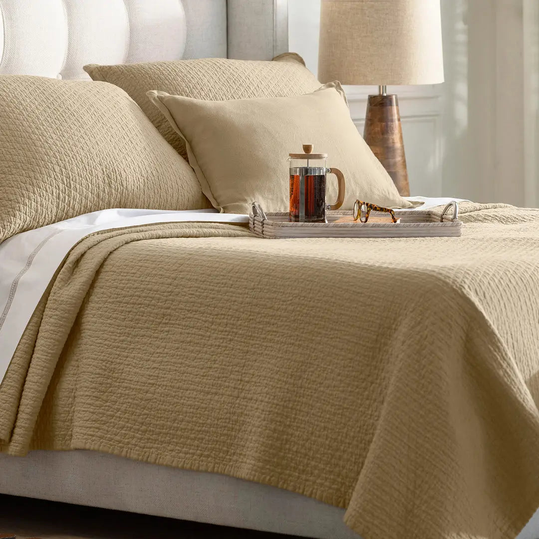 Dawn Diamond Quilted Queen Coverlet in the warm neutral golden latte color, showing the quilted texture and flange edge on a bed.