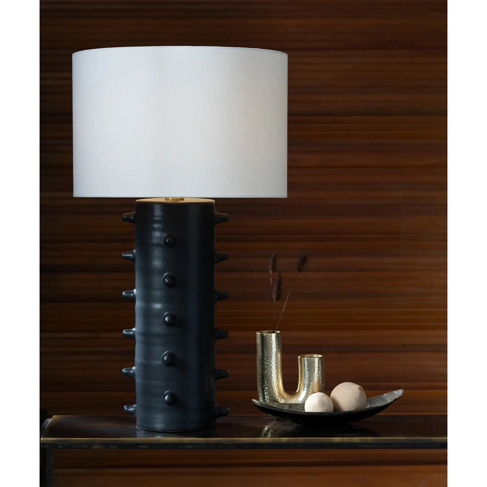 Table lamp with a unique black base and white shade on a wooden surface.