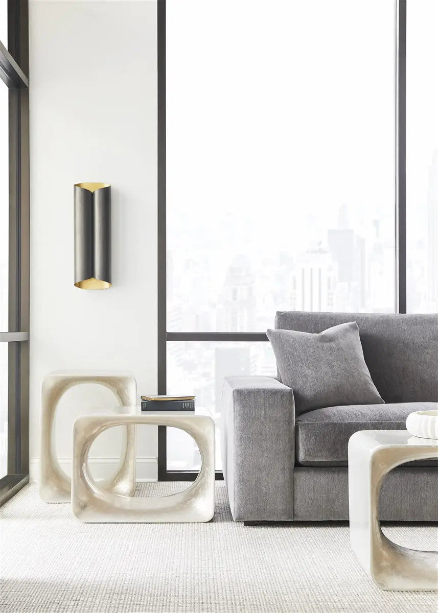 Modern living room with a gray sofa, white side table, and decorative wall light.