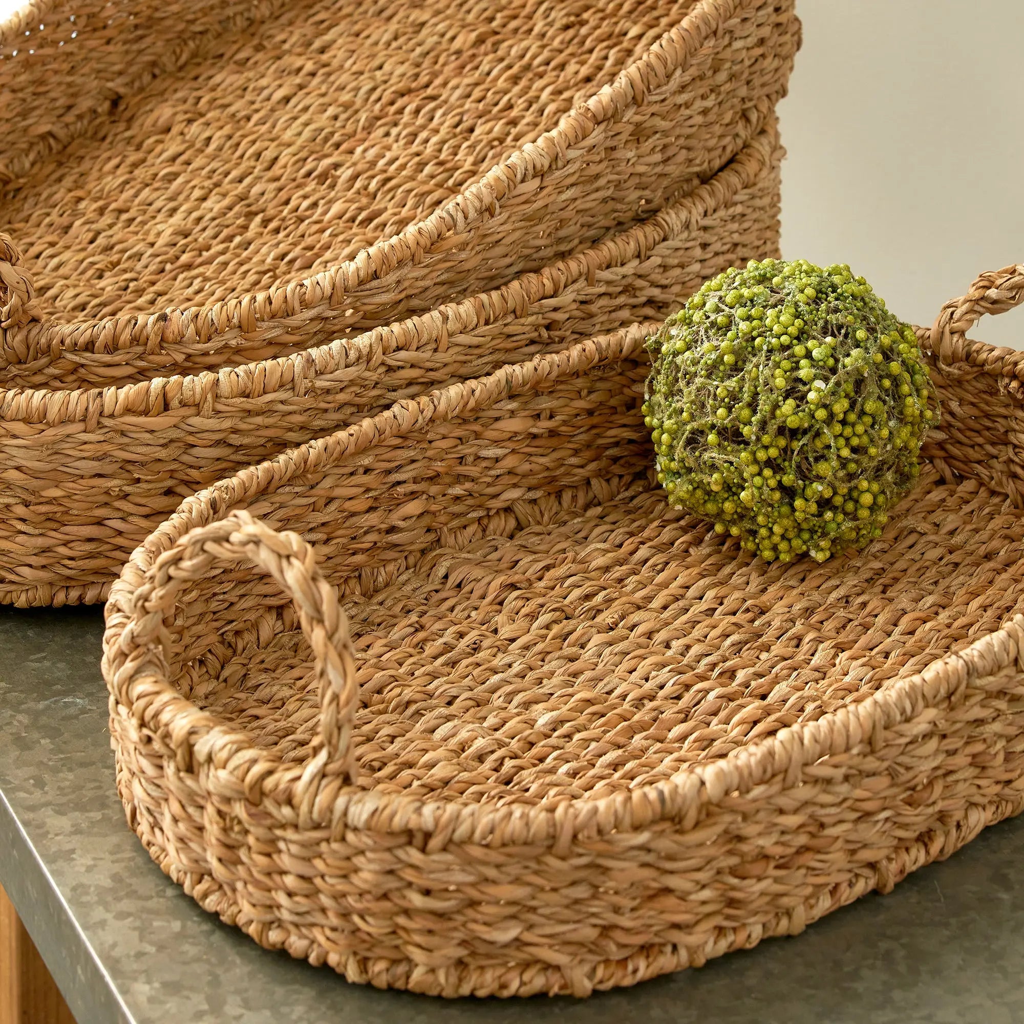 Woven baskets with a decorative ball on a neutral background
