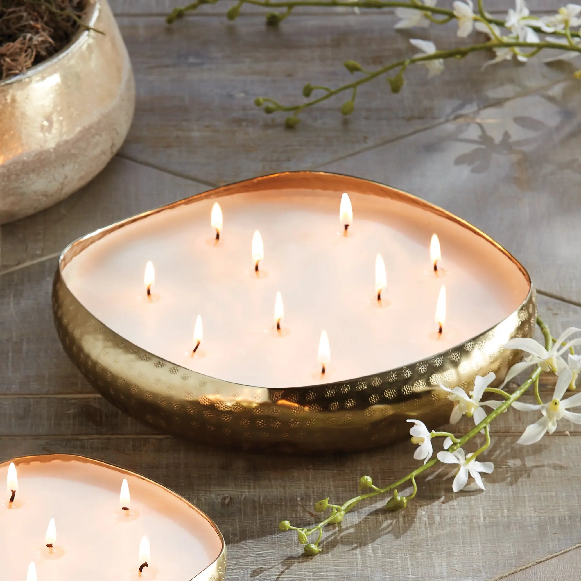 Heart-shaped candle with multiple flames on a wooden surface with white flowers.