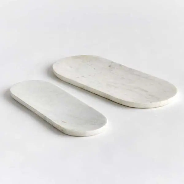 A set of two oval white marble trays, with a large and small tray displayed together, showcasing the unique natural veining in the stone.