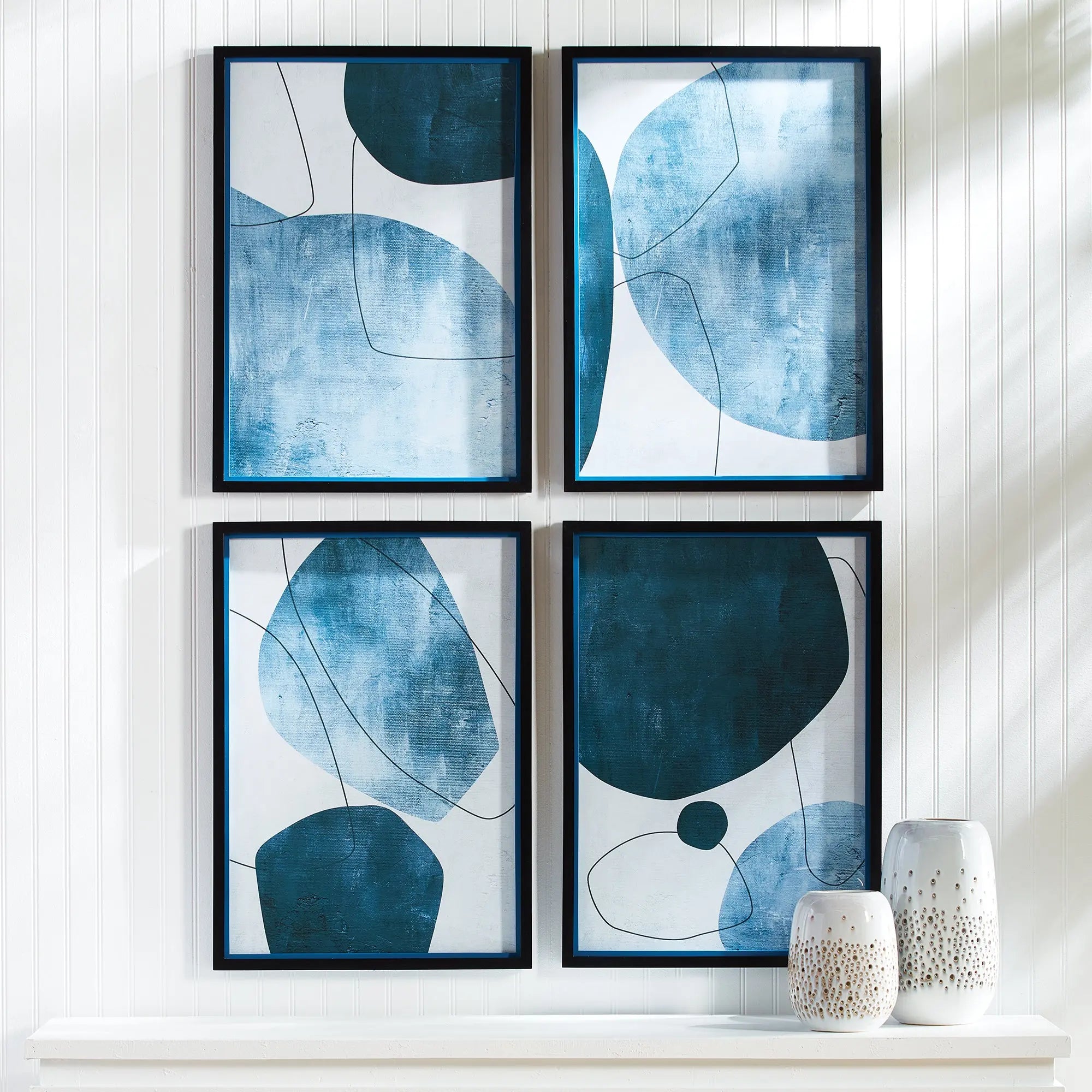 Set of four contemporary abstract wall art prints with black shadowbox frames, featuring white, black, and blue geometric lines and shapes.