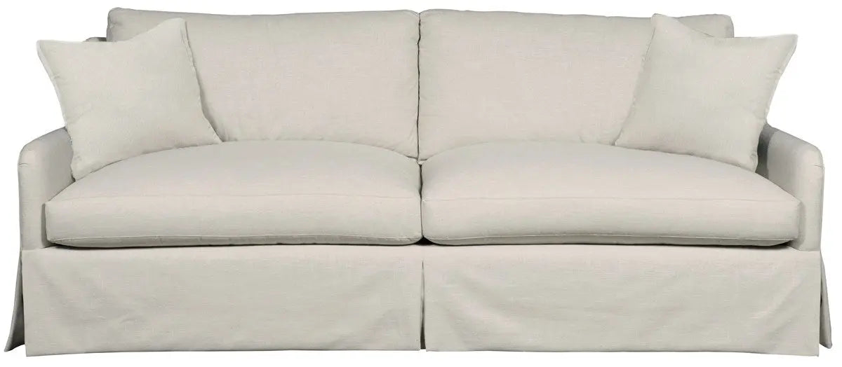 Fisher Sofa, a long, classic slipcovered sofa with a skirted base, deep cushions, and two throw pillows, upholstered in a light, neutral Nuzzle Linen fabric.