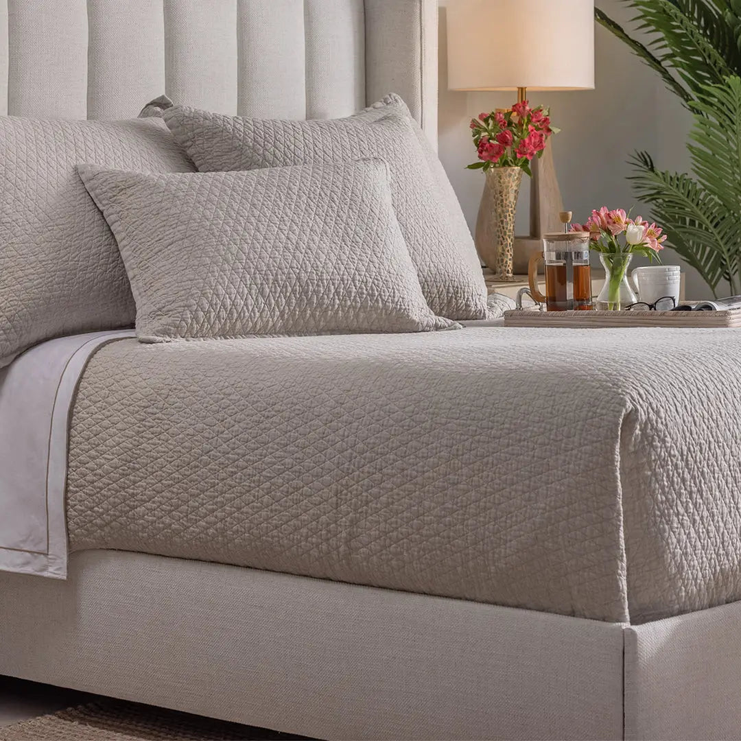 Dawn Diamond Quilted Queen Coverlet in the warm neutral golden latte color, showing the quilted texture and flange edge on a bed.